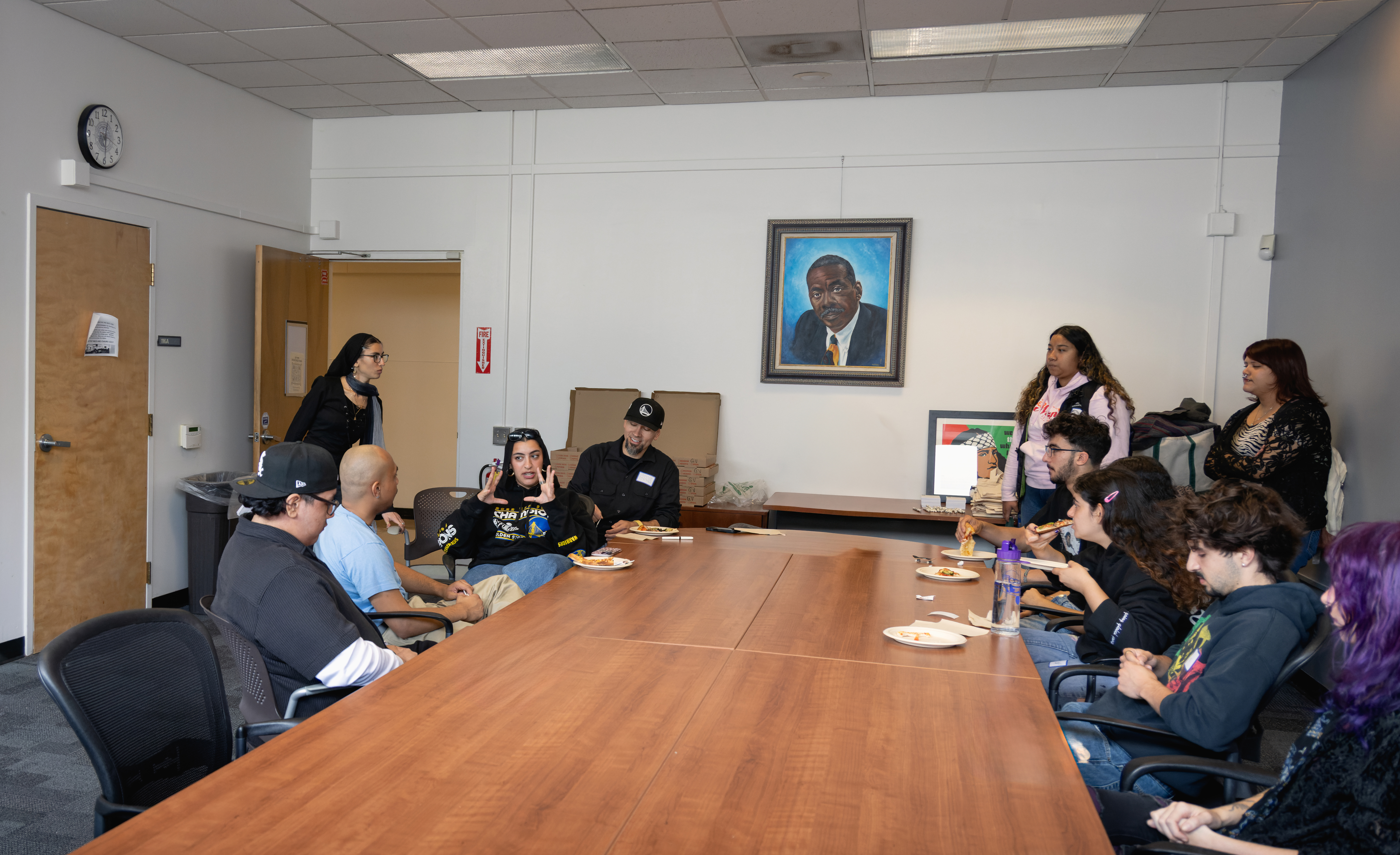 Attendees sitting around the table, eating pizza.