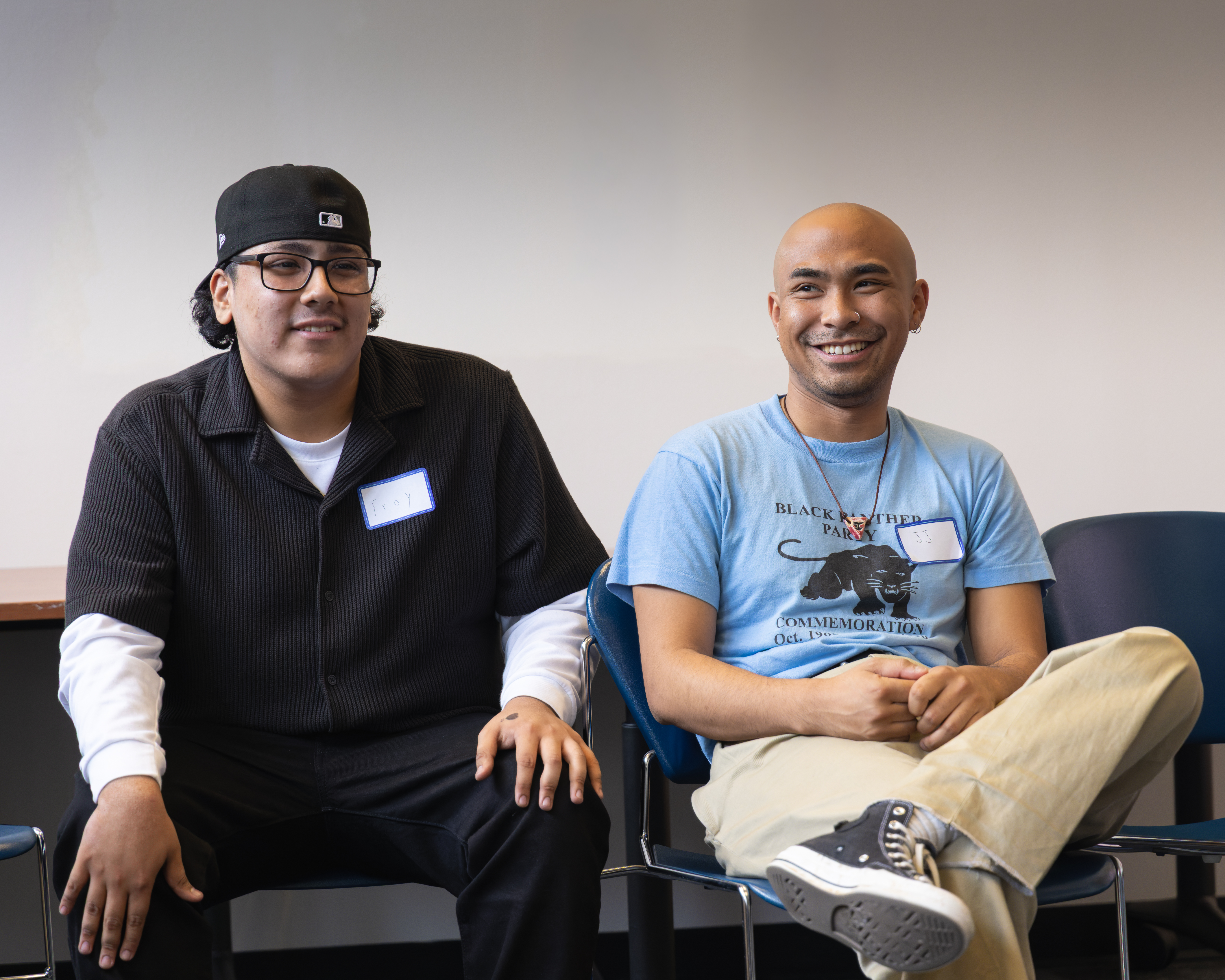 Two students sitting next to each other, smiling at the group.