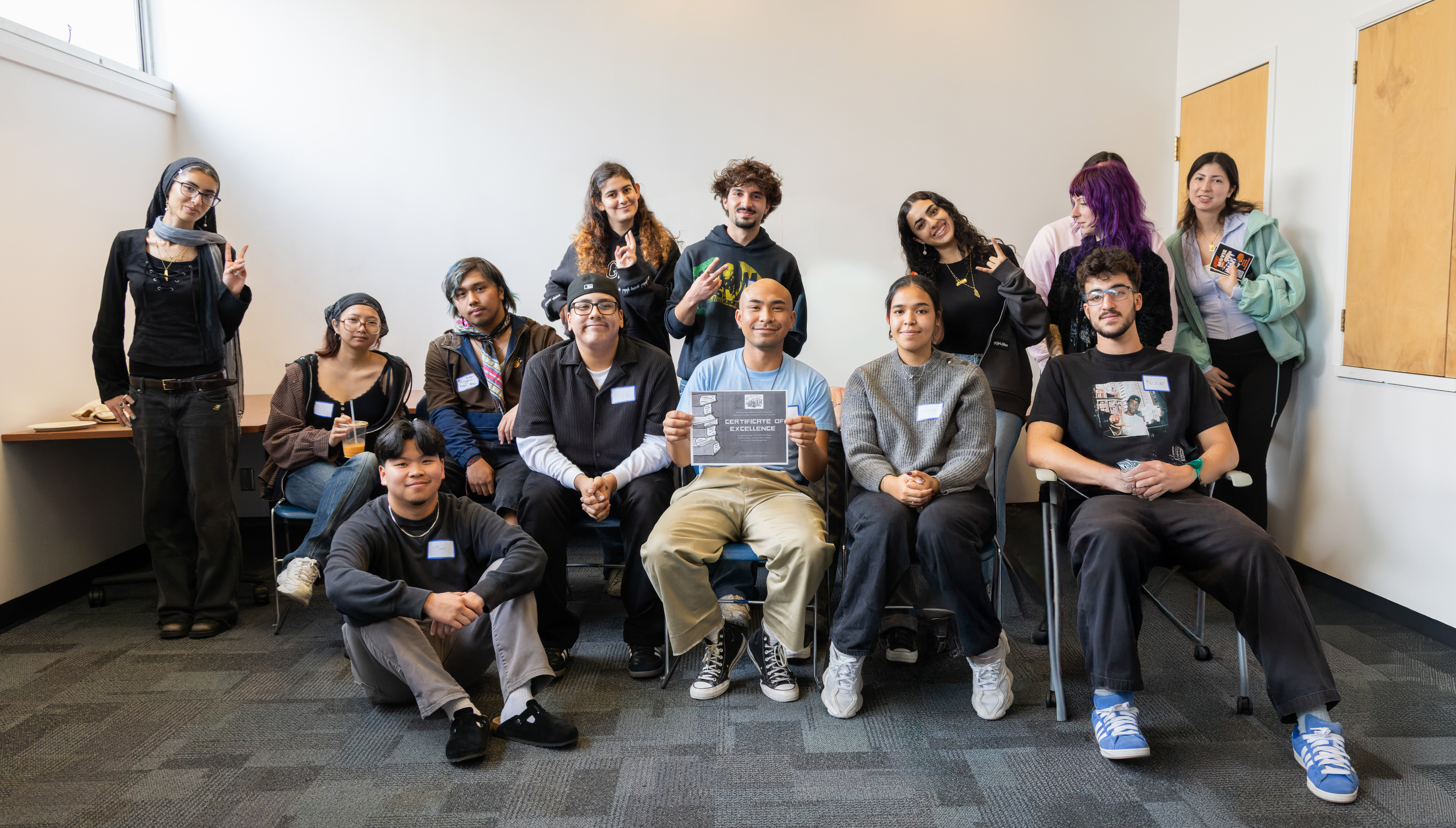 The students posing for a group photo, with one in the center holding a "Certificate of Excellence" for participating in the trivia competition.